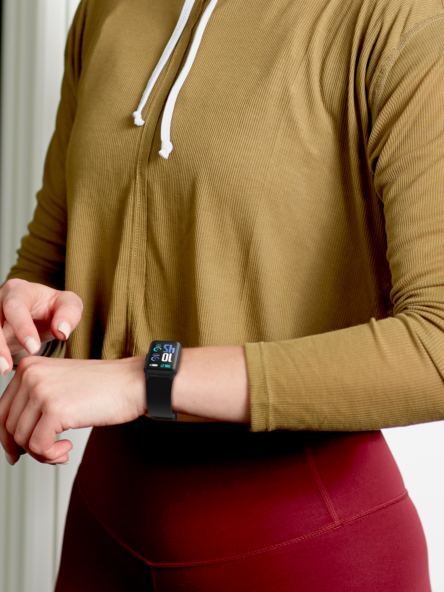 Person wearing a brown long-sleeve top and red leggings, using a smartphone with a fitness tracker on their wrist.